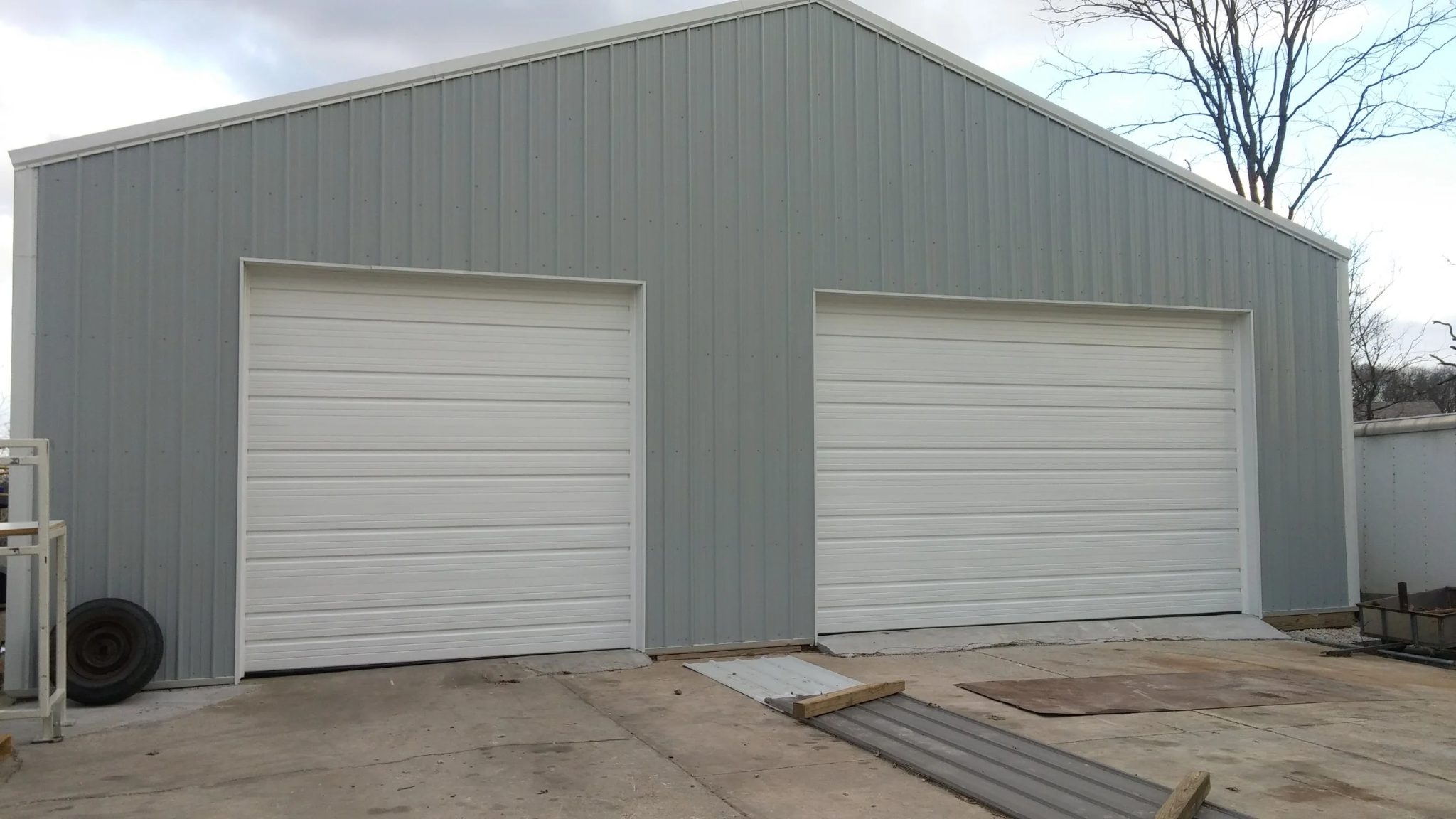 Commercial steel building with two newly installed white sectional garage doors