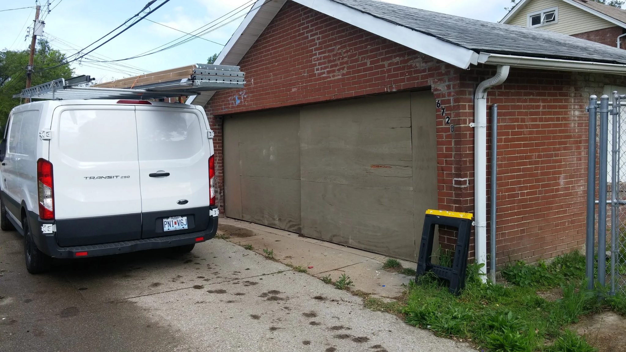 Service van behind a brick garage with the old wood door still in place