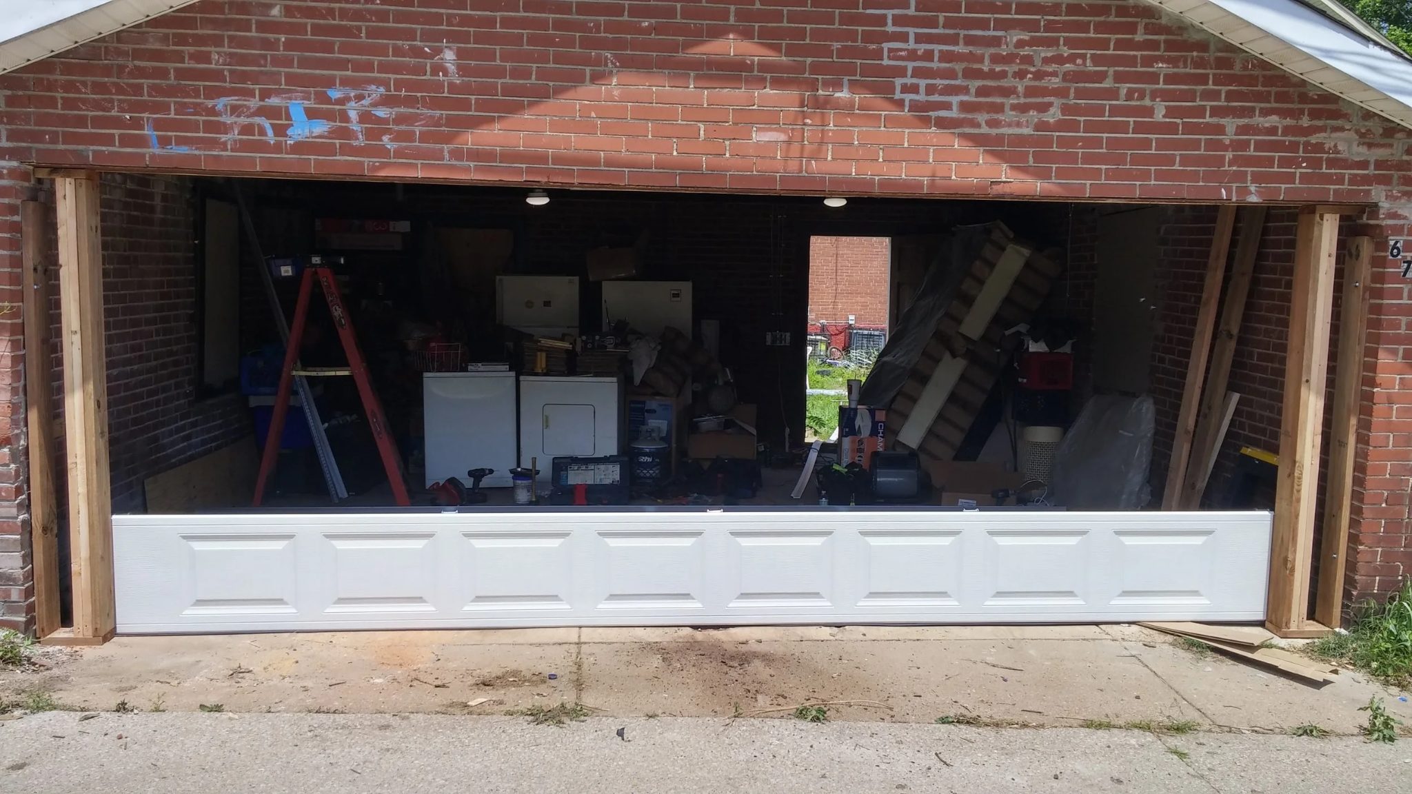 Bottom panels of a new white sectional door installed in the brick garage opening